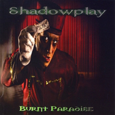 Shadowplay Burnt Paradise album cover with goth man dressed in red vintage clothing standing holding a ticket